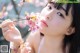 A woman holding a branch of a tree with pink flowers.