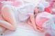 A woman laying on a bed with a pink pillow.