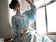 A woman in a blue hanbok sitting on a window sill.