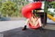 A naked woman sitting on a red slide in a park.