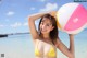 A woman in a yellow bikini holding a beach ball.