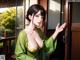 A woman in a green kimono standing in front of a door.