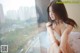 A woman sitting on a window sill looking out a window.