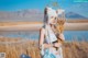 A woman in a white and blue outfit holding a bunch of wheat.