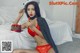 A woman in a red lingerie sitting on a bed.