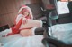 A woman in a santa outfit laying on a bed.