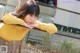 A woman leaning against a fence with her hand on her chin.