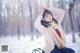 A woman sitting on a bench in the snow.
